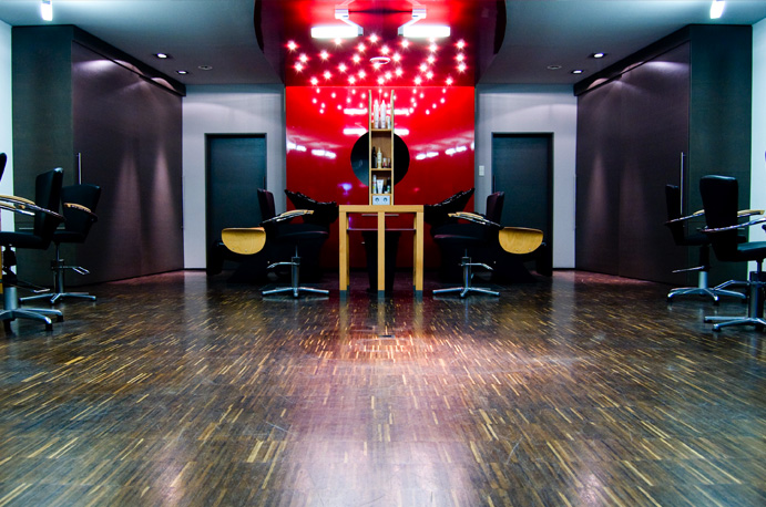 Blick in den Salon mit dunklem Holzboden und roter Akzentwand